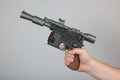 Hand holding a black gun against a brick wall