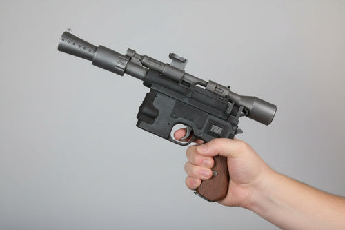 Hand holding a black gun against a brick wall