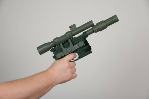 Hand holding a black gun against a brick wall